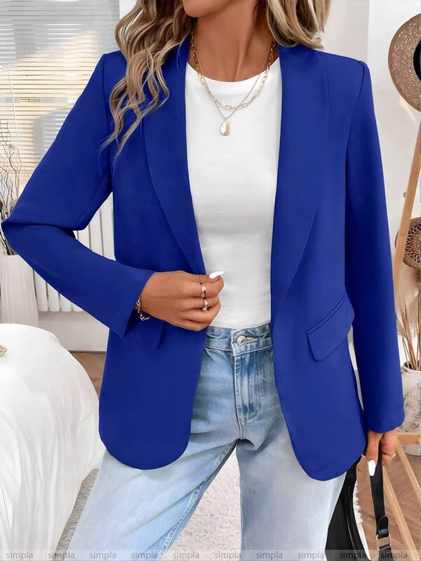 Person wearing a blue blazer over a white top and light blue jeans indoors.
