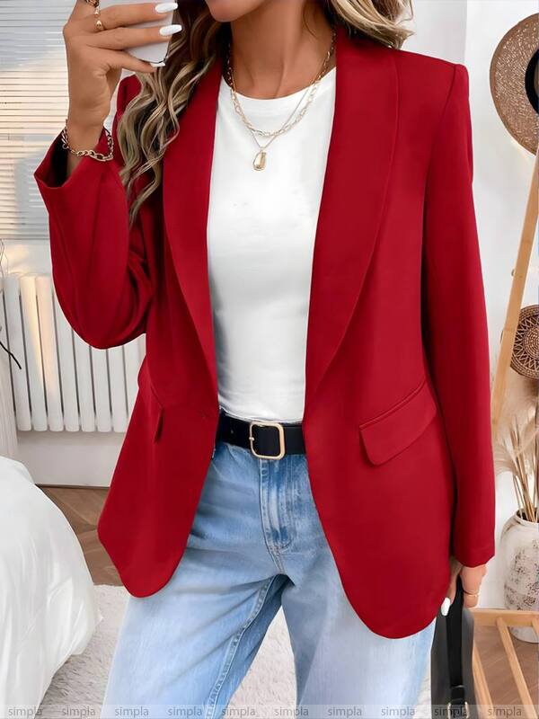 Person wearing a red blazer, white top, and blue jeans indoors.