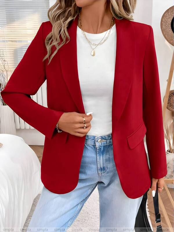 Person wearing a red blazer over a white top and light blue jeans indoors.