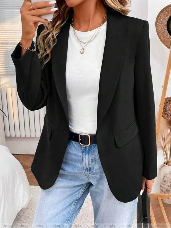 Person wearing a black blazer, white top, and blue jeans indoors.