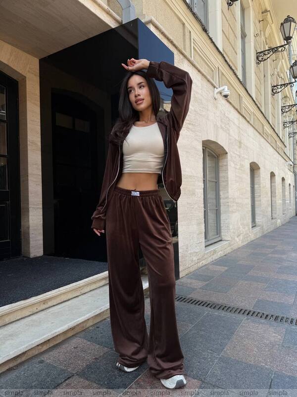 Woman in brown tracksuit standing on a street with a building in the background