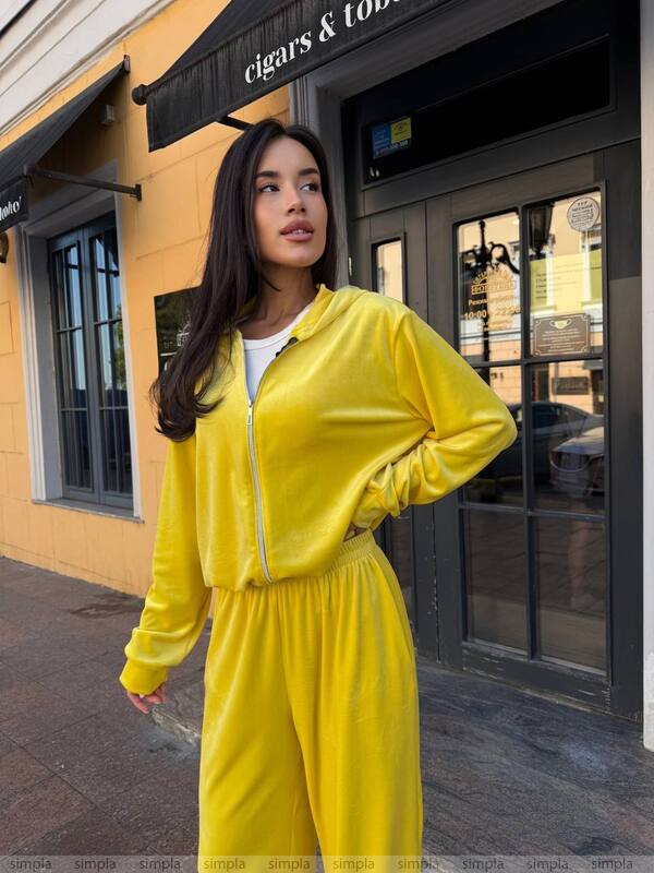 Woman in a yellow tracksuit standing in front of a building entrance.