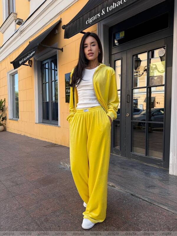 Woman in a yellow outfit standing outside a building with a yellow facade.