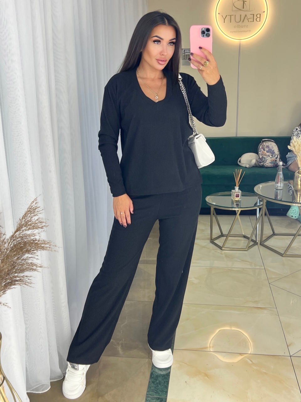 Woman taking a mirror selfie wearing a navy blue outfit in a stylish room.