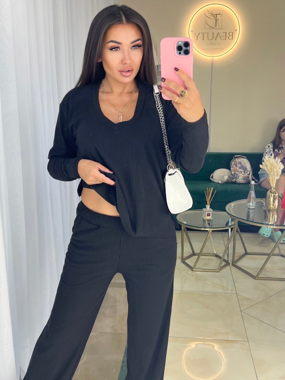 Woman taking a mirror selfie wearing a black outfit in a living room.