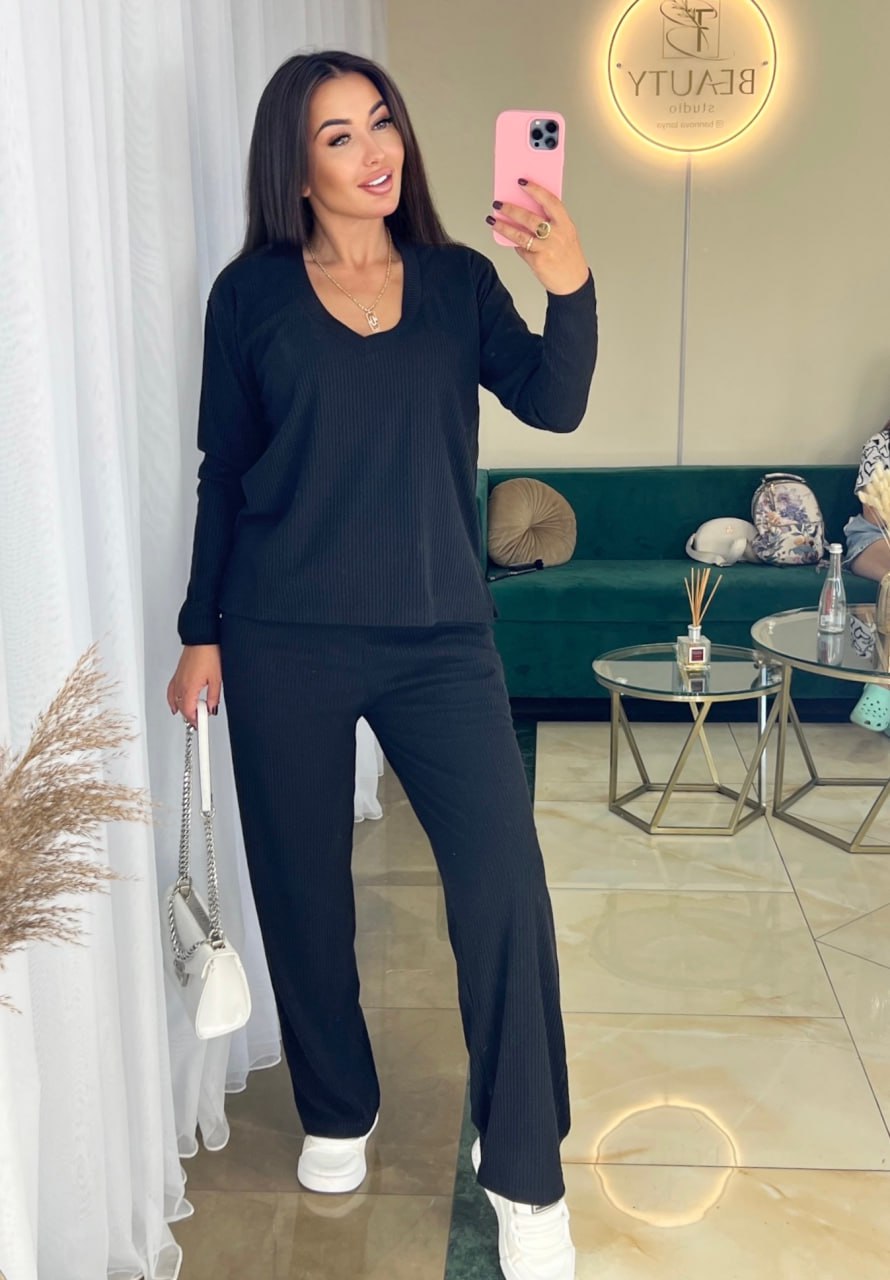 Woman taking a mirror selfie wearing a black outfit in a stylish room.