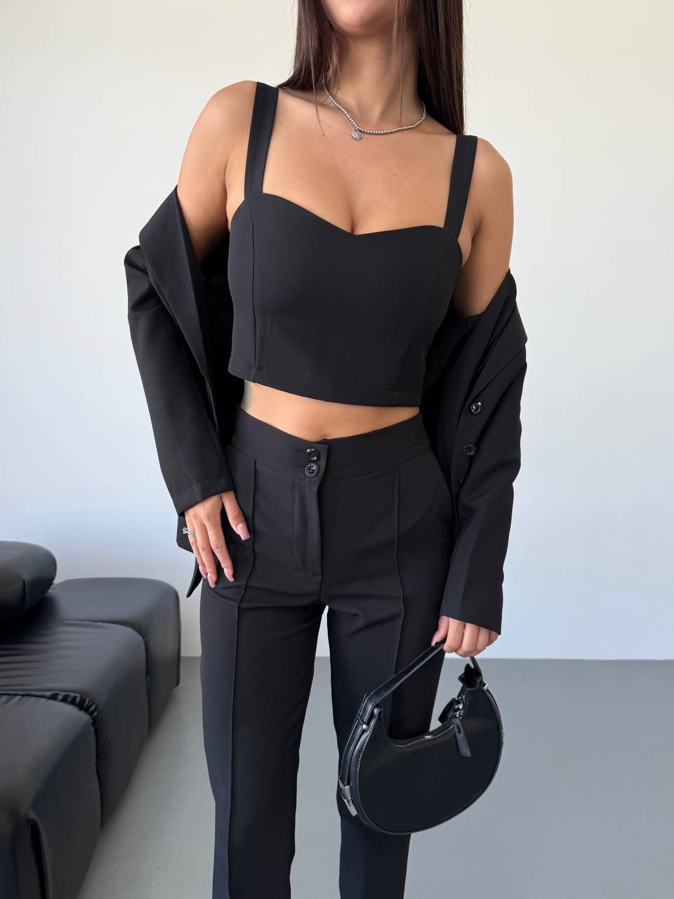 Person wearing a black outfit with a plain background