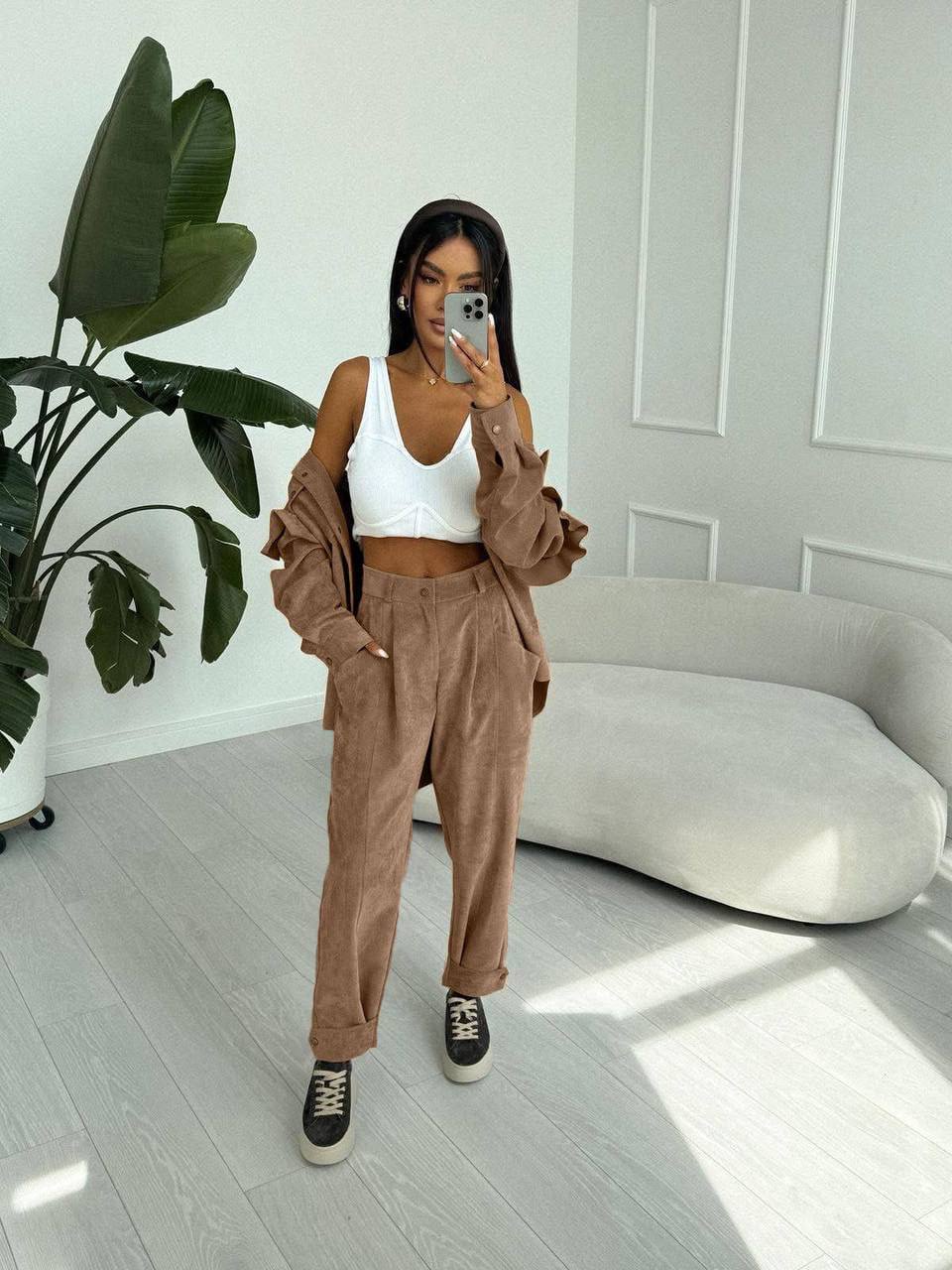 Woman taking a mirror selfie in a stylish outfit in a modern room.