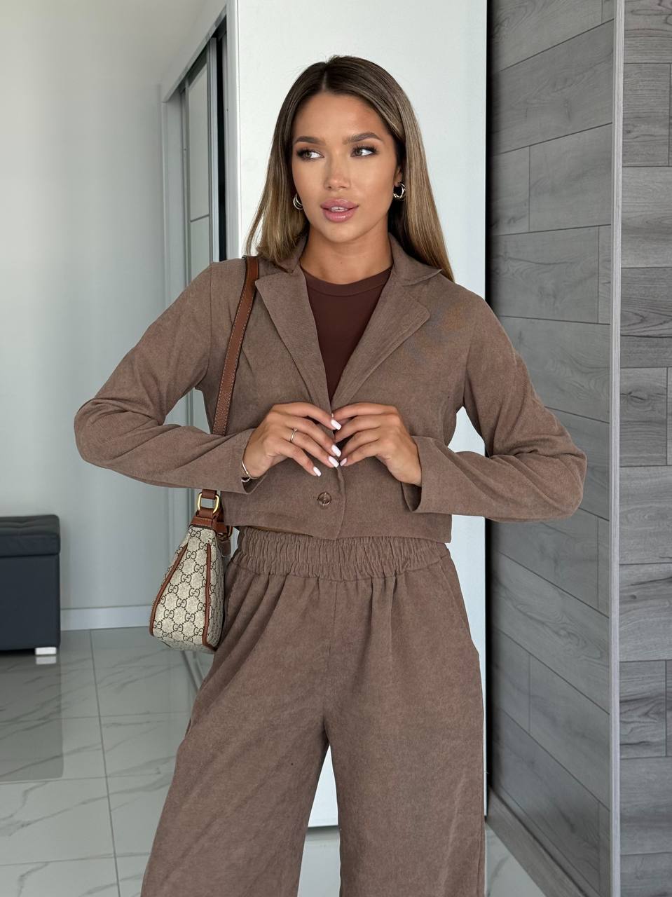 Woman in a brown outfit standing in a modern interior setting