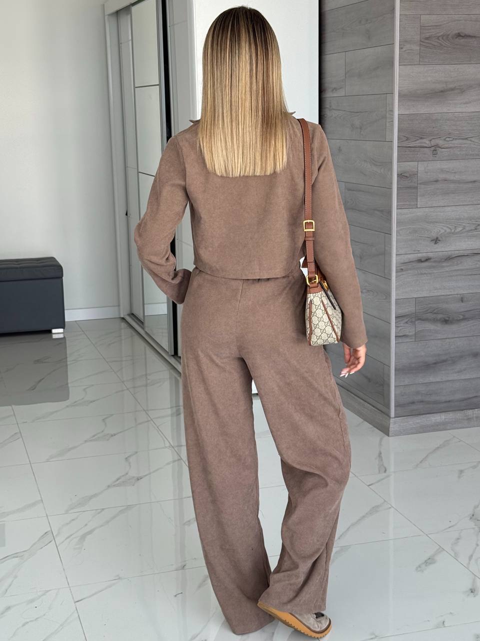 Woman in a brown outfit standing in a modern interior setting