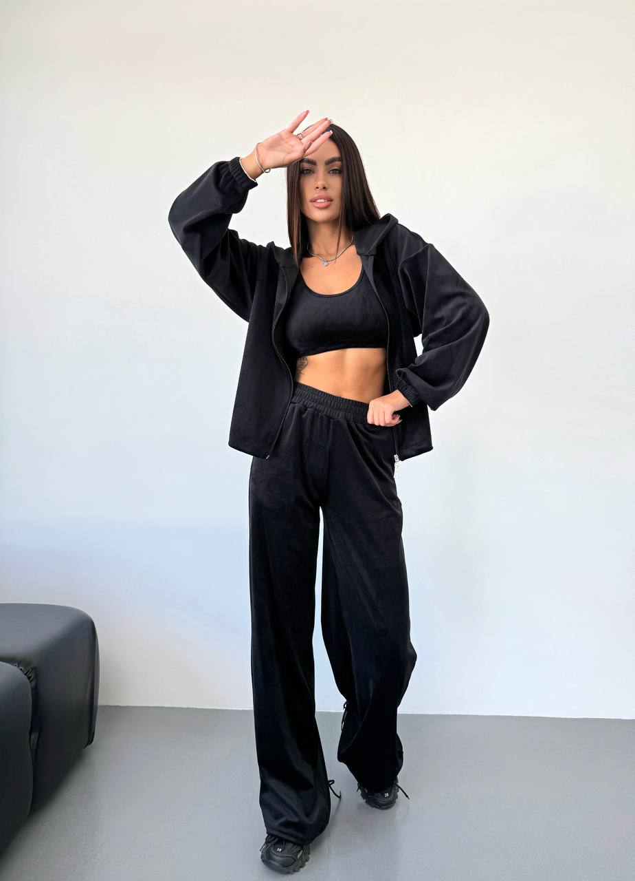 Person wearing a black tracksuit against a plain background