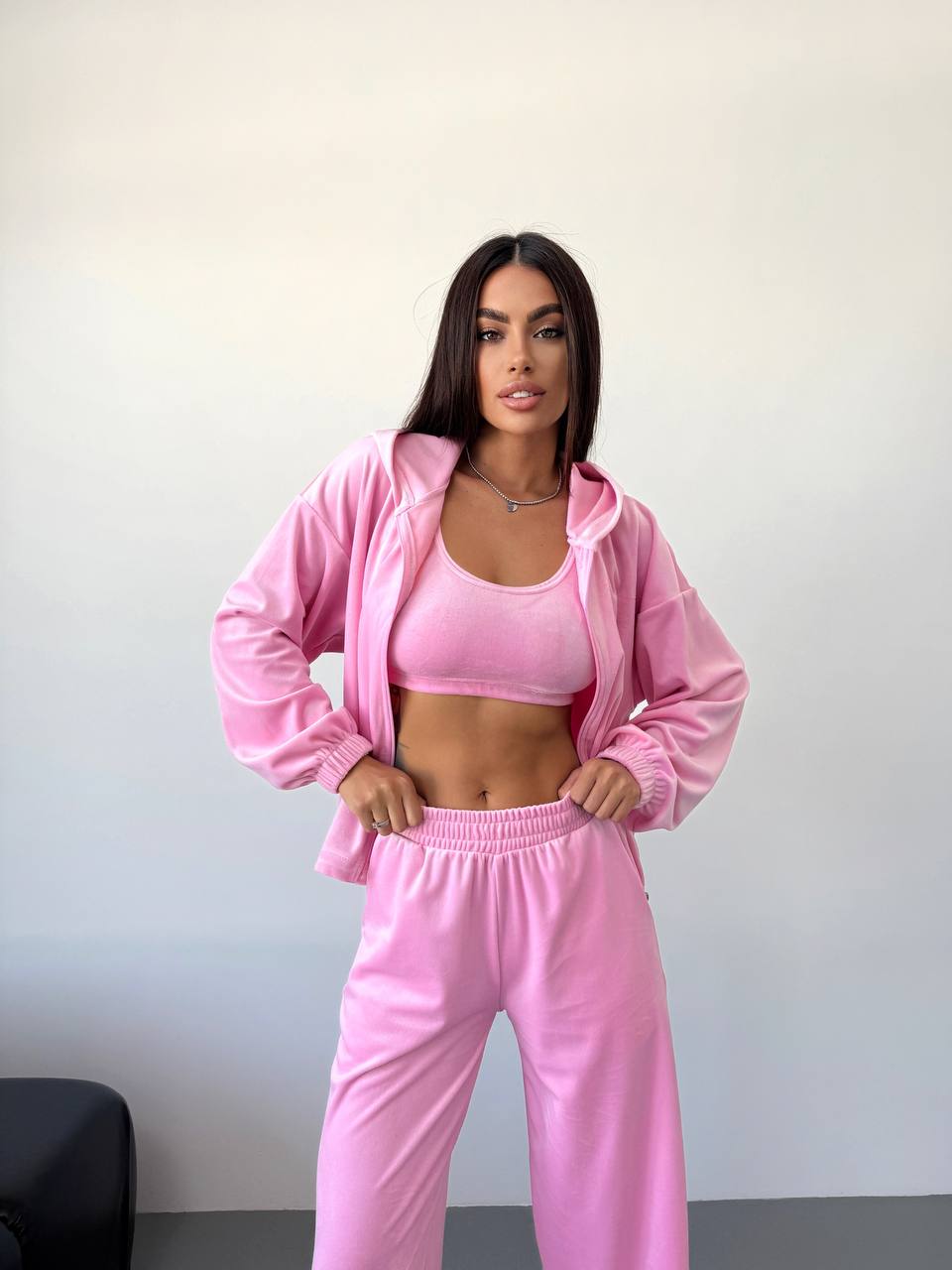Woman wearing a pink tracksuit against a plain background