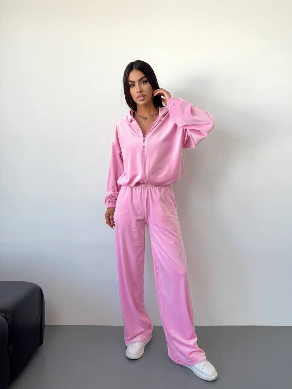 Person wearing a pink tracksuit standing against a plain background