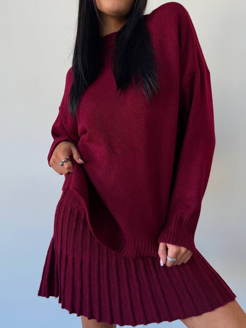Person wearing a burgundy sweater dress against a plain background