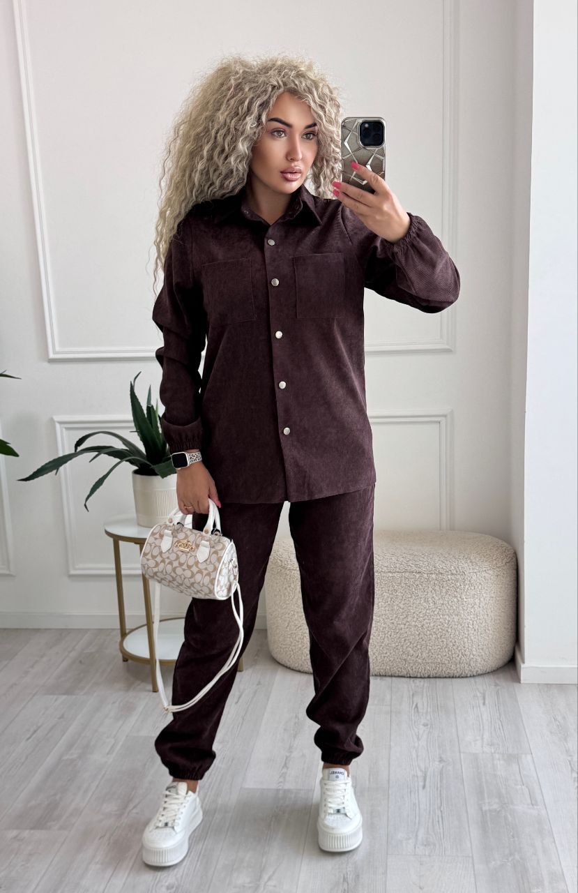 Person wearing a brown outfit with white sneakers in a room.