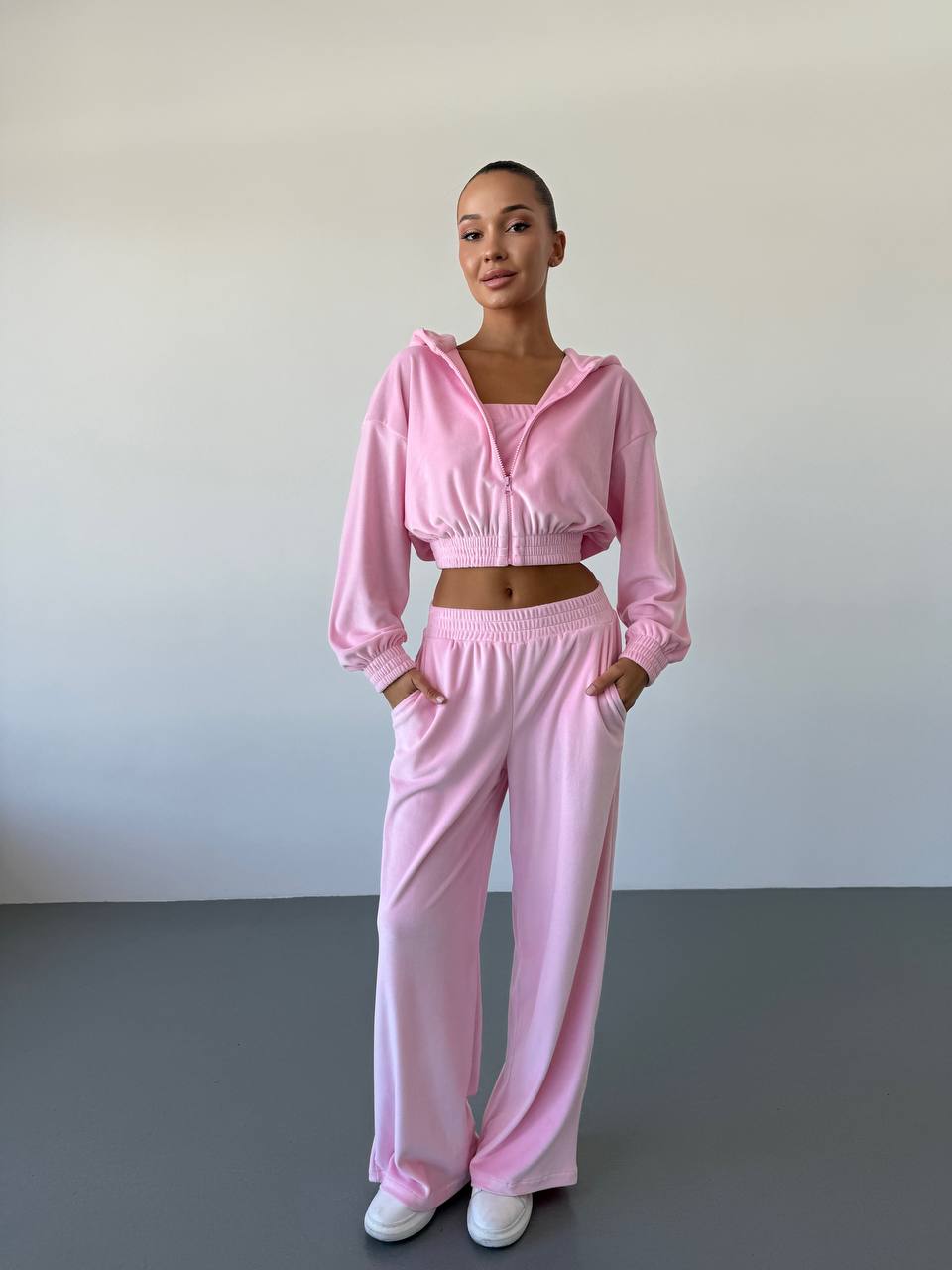 Person wearing a pink tracksuit against a plain background