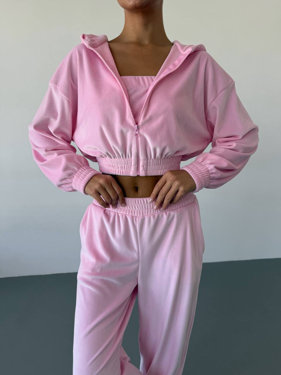 Person wearing a pink tracksuit against a neutral background