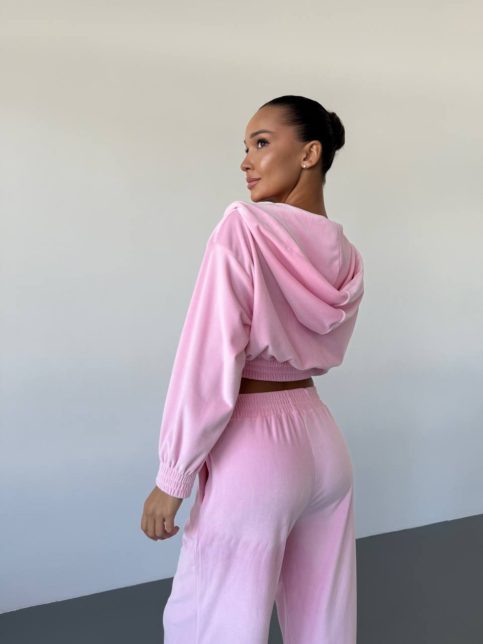 Person wearing a pink tracksuit against a plain background