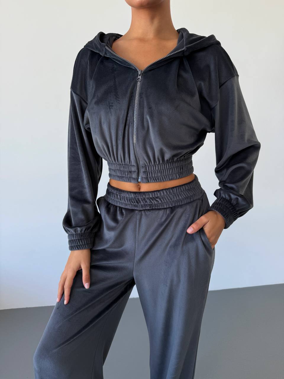 Person wearing a gray tracksuit against a plain background