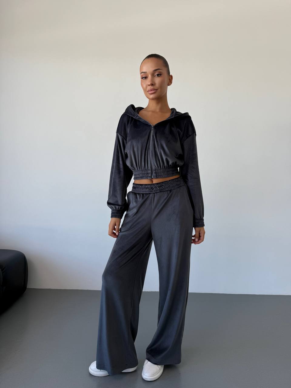 Person wearing a black outfit standing against a plain background