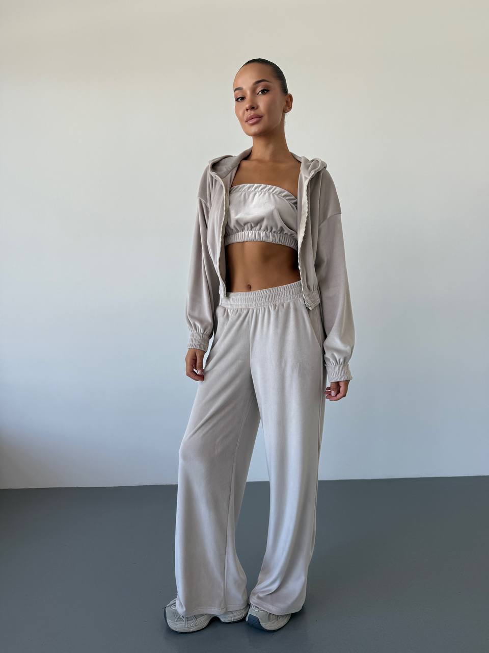Woman wearing a light gray tracksuit against a plain background