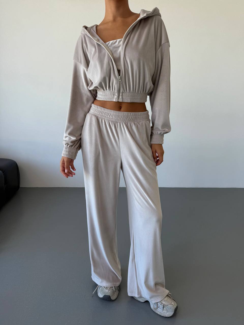 Person wearing a light gray tracksuit against a plain background