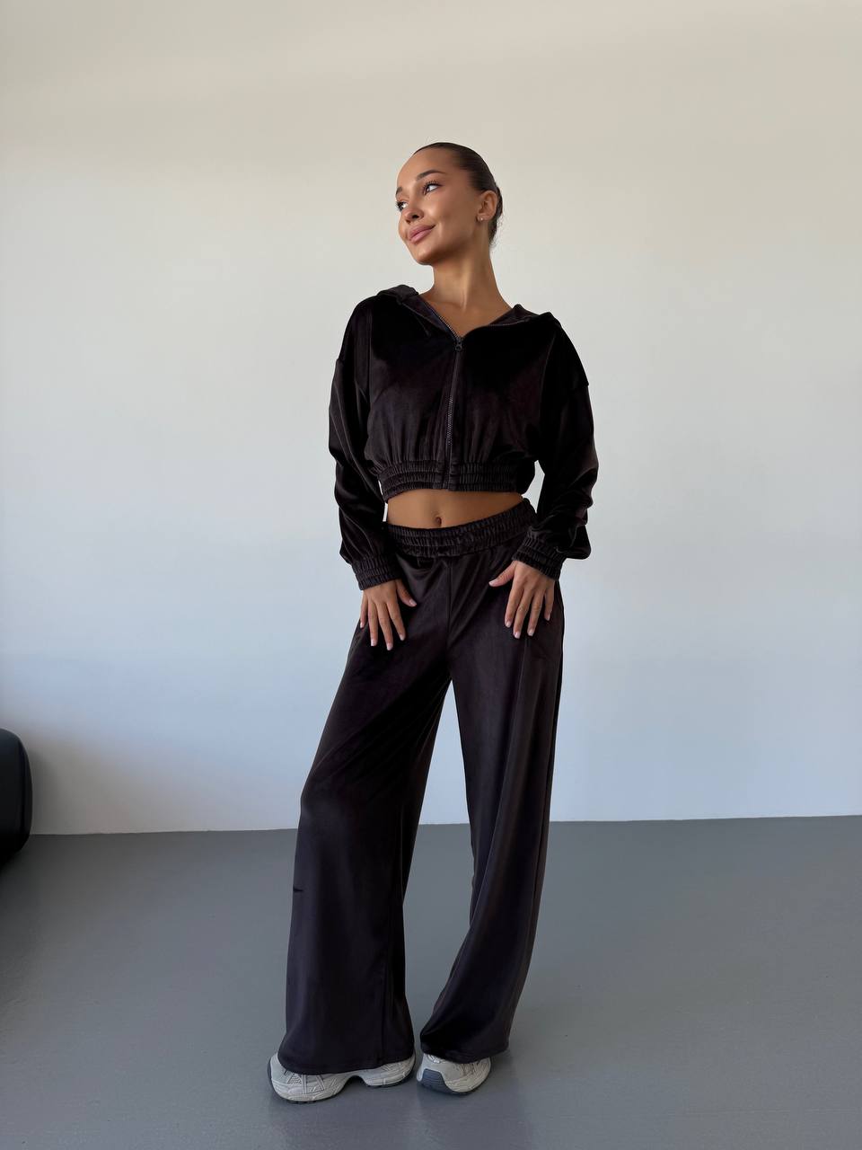 Person wearing a black outfit standing against a plain background