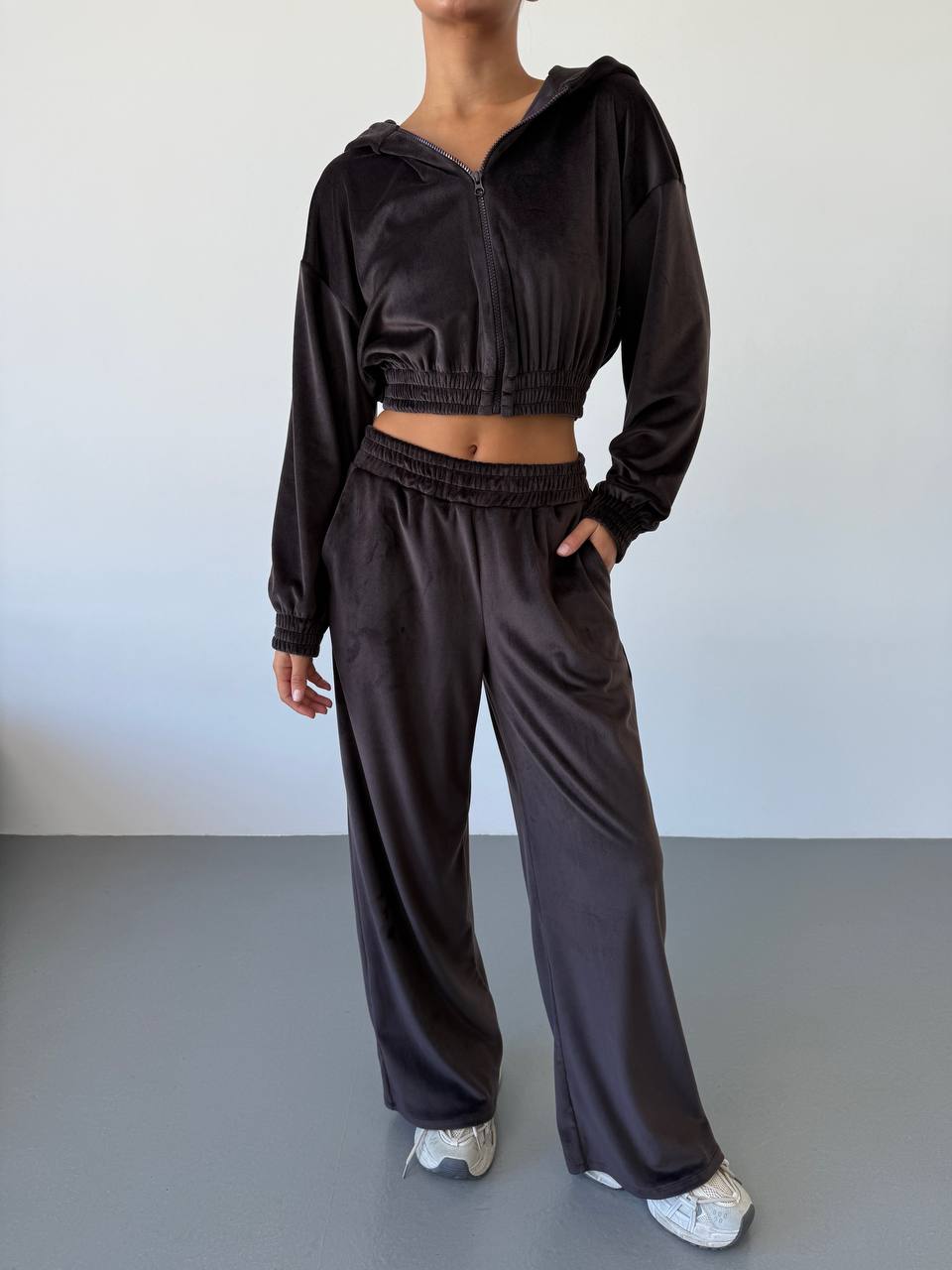 Person wearing a dark brown tracksuit against a plain background