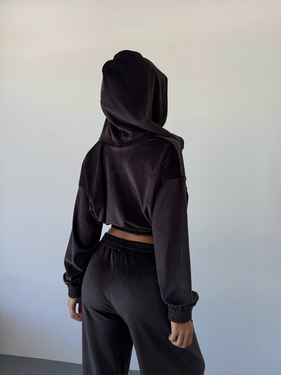 Person wearing a black hoodie and pants against a plain background