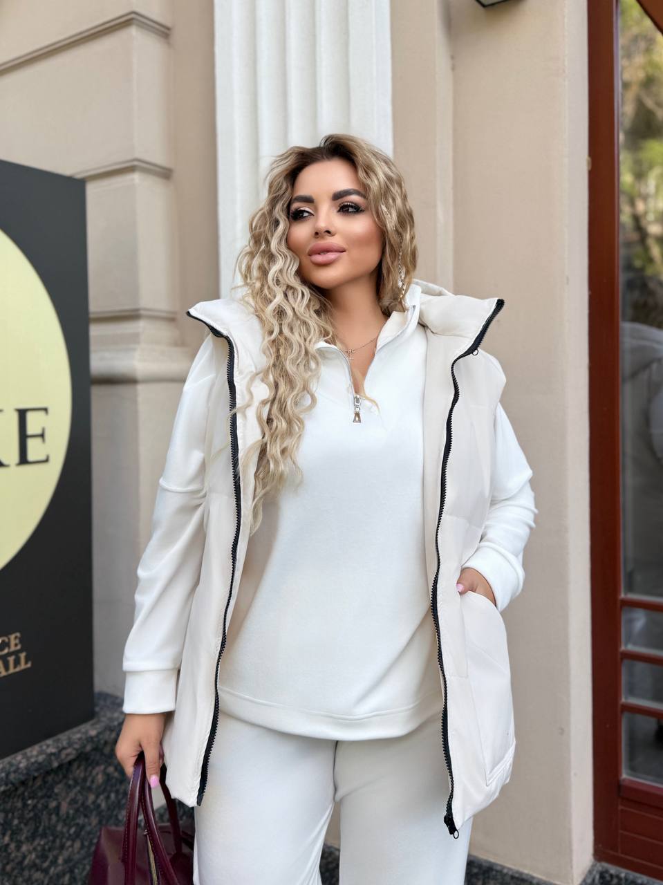 Woman in a white outfit standing outside a building