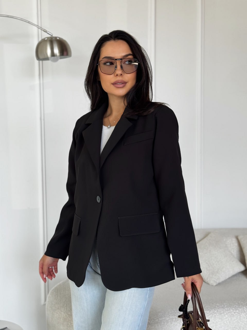 Woman wearing a black blazer and glasses indoors.