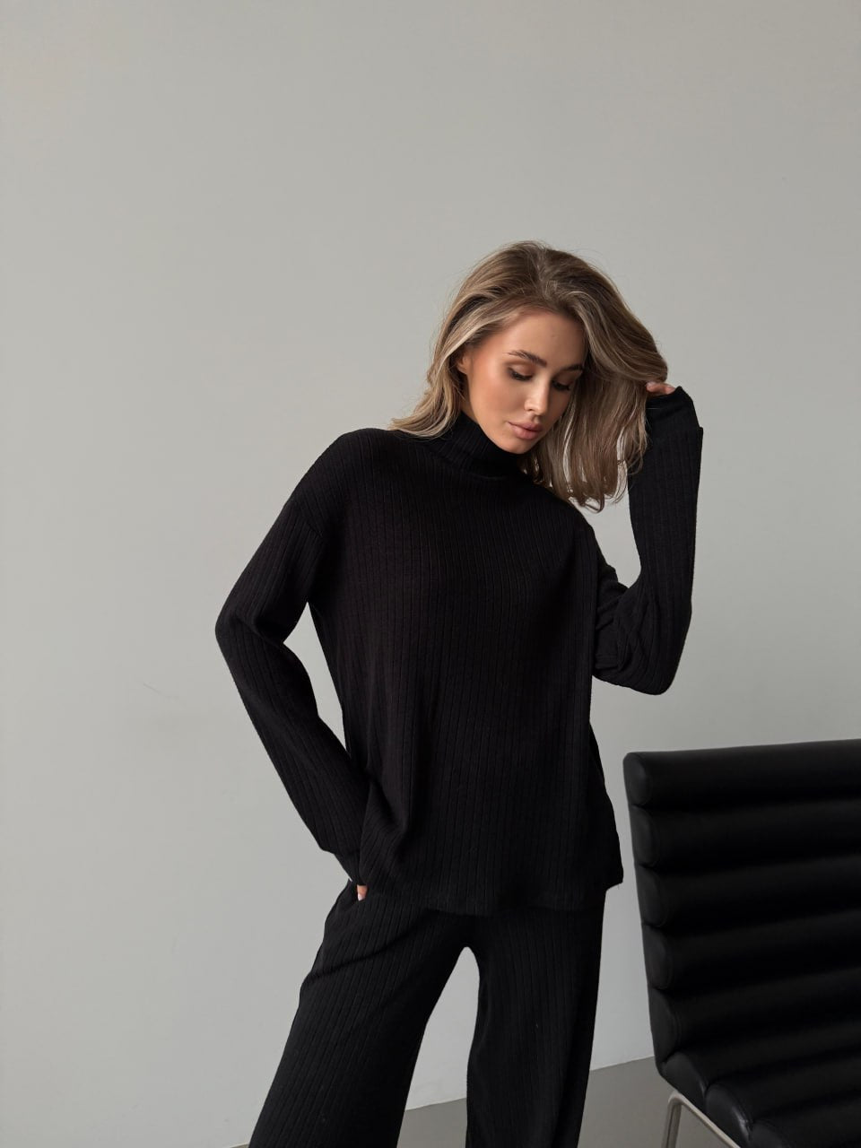 Woman wearing a black outfit against a gray background