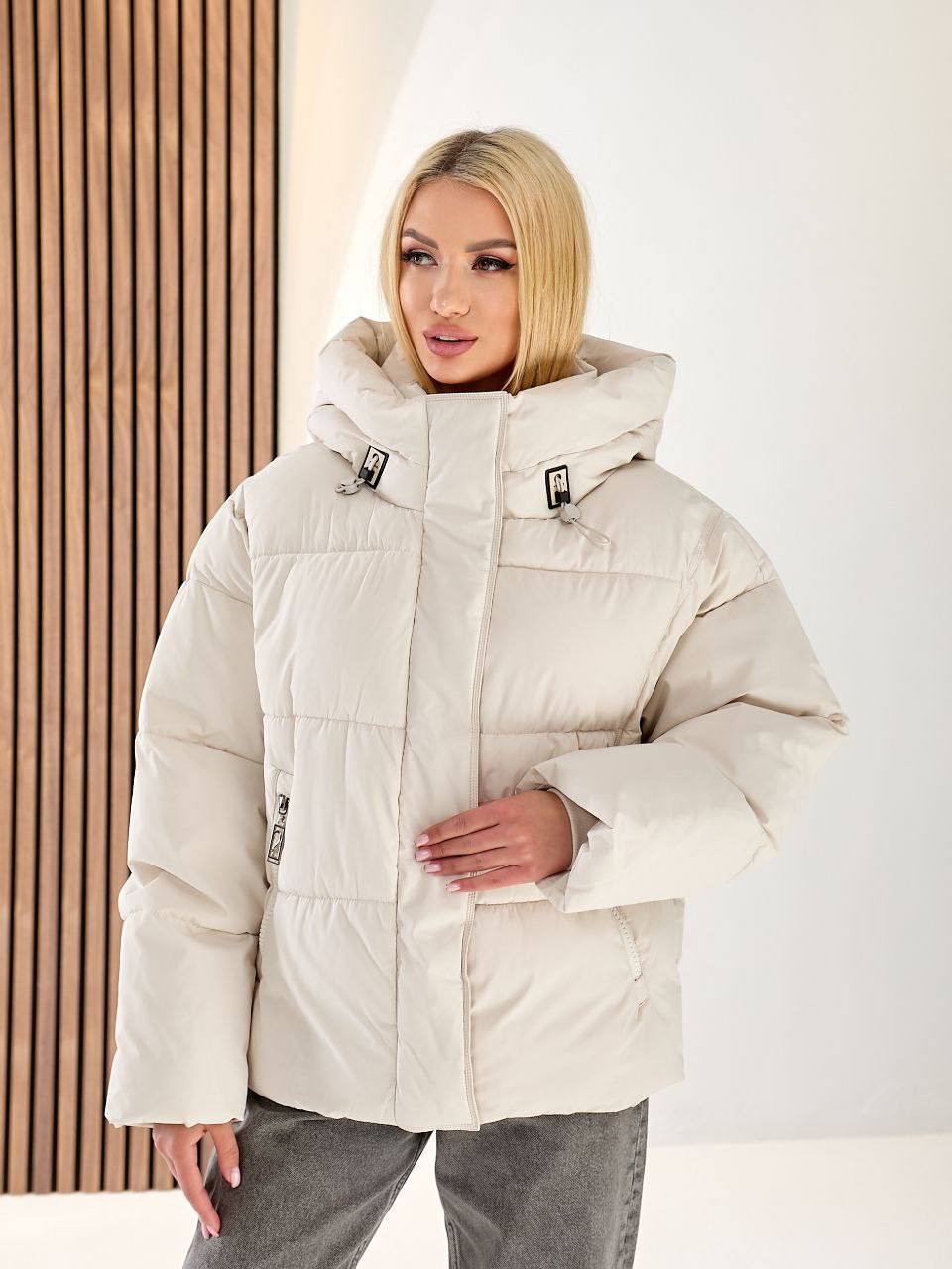 Woman wearing a beige winter jacket against a white background