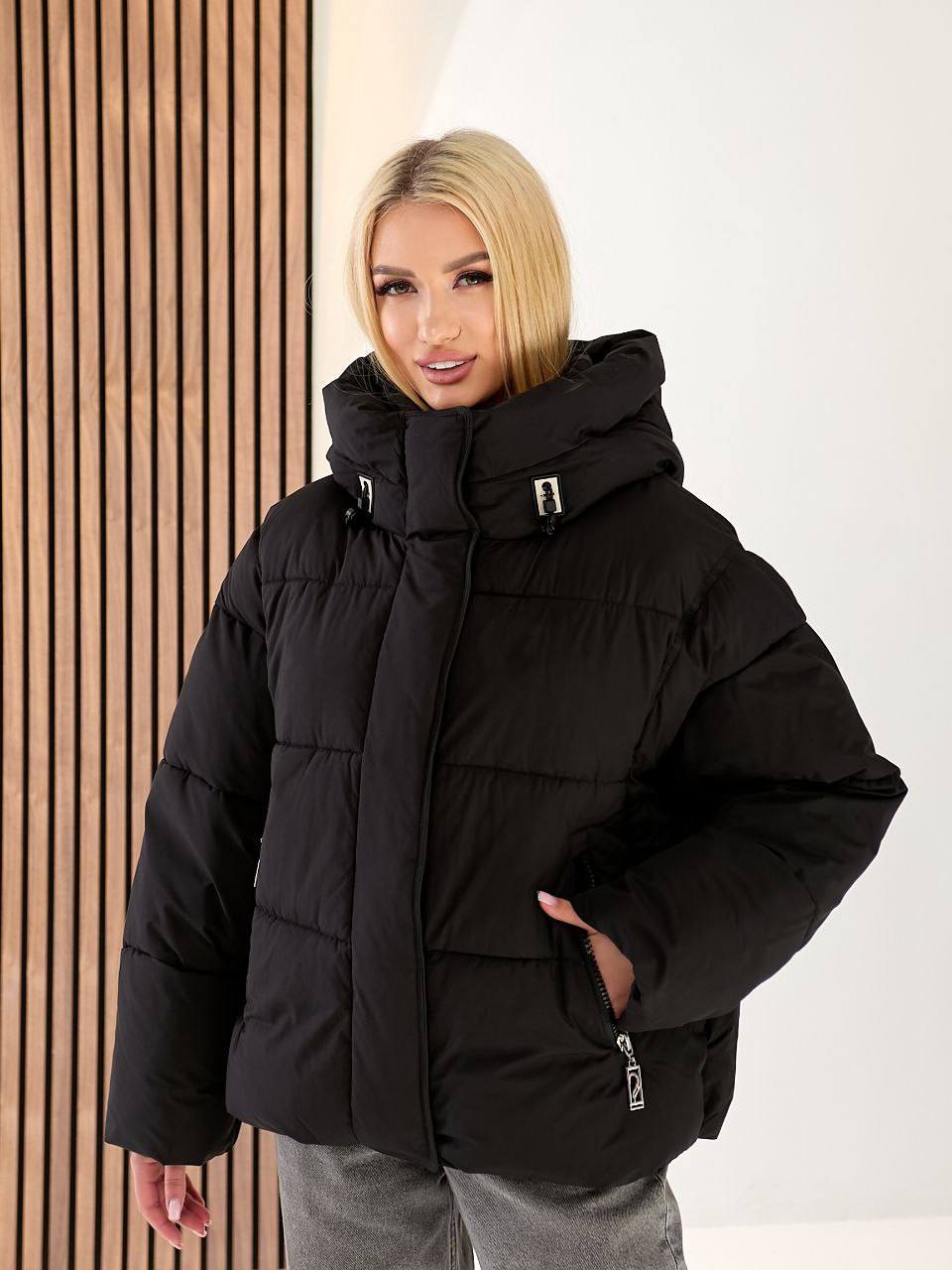 Woman wearing a black puffer jacket against a white background