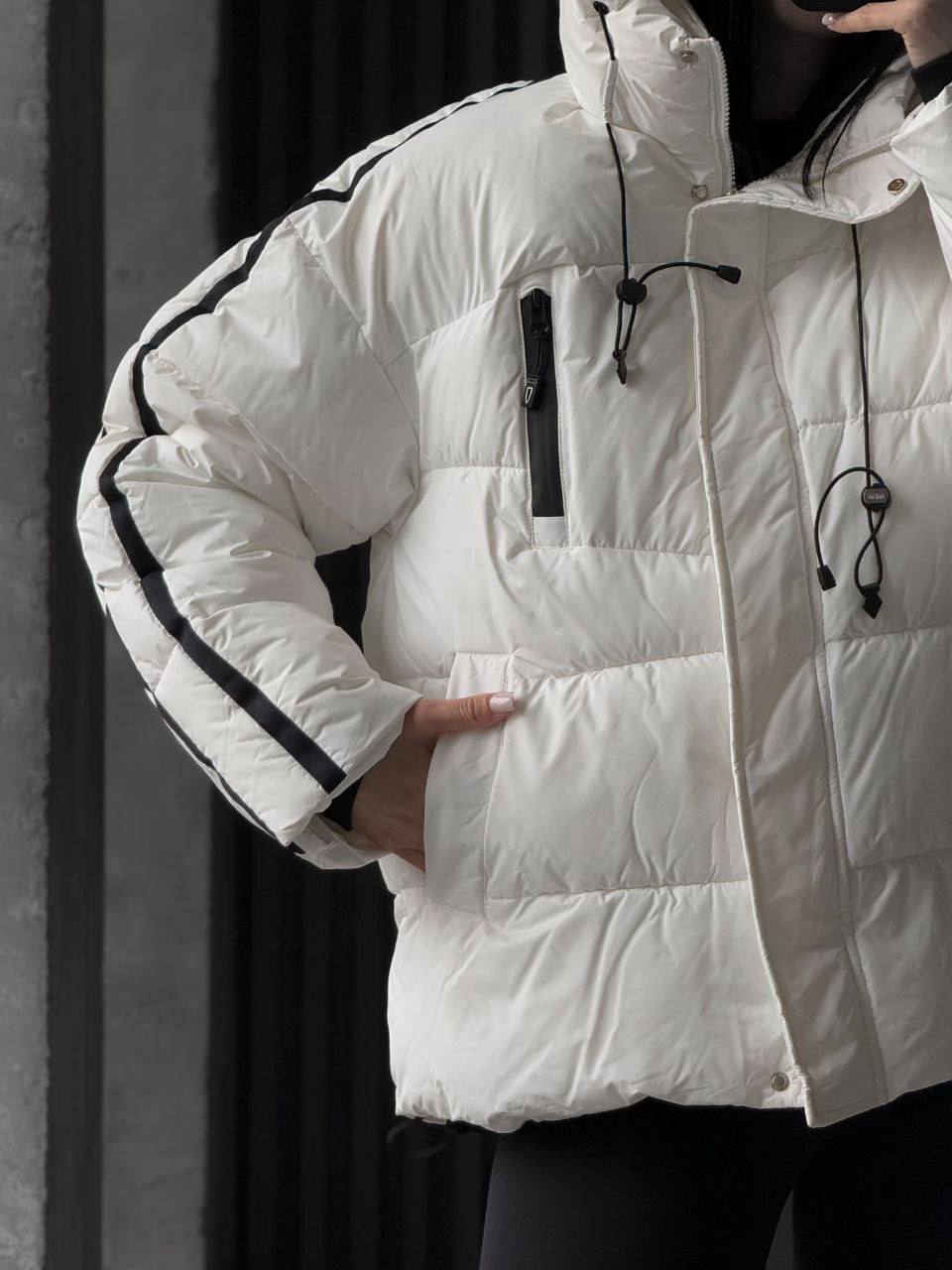 White puffer jacket with black accents worn by a person against a dark background