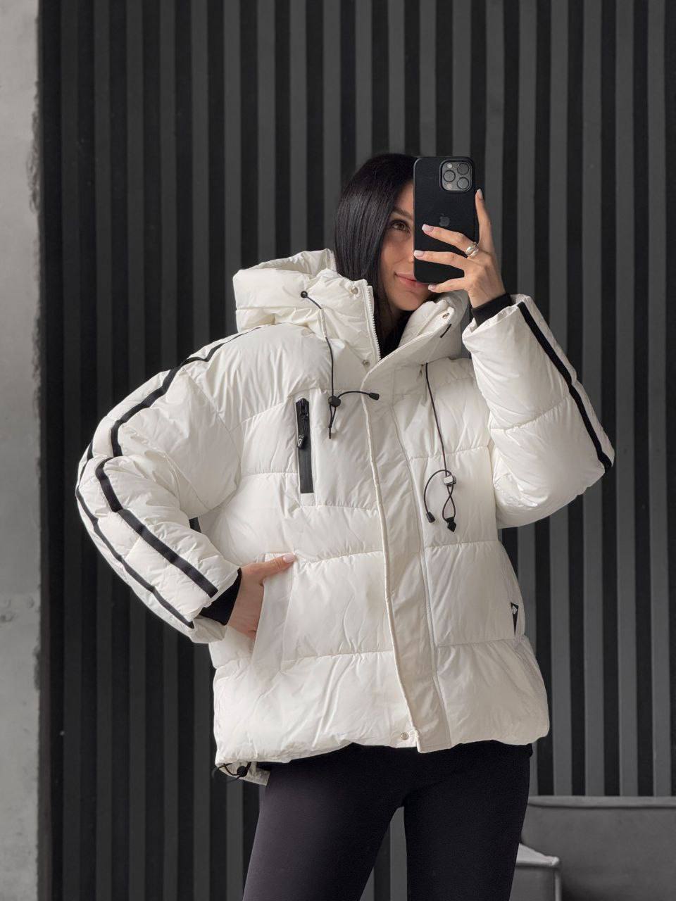 Person wearing a white puffer jacket with black accents, taking a mirror selfie.