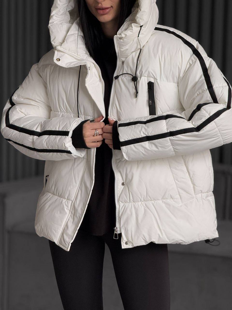 White puffer jacket with black accents worn by a person against a dark background