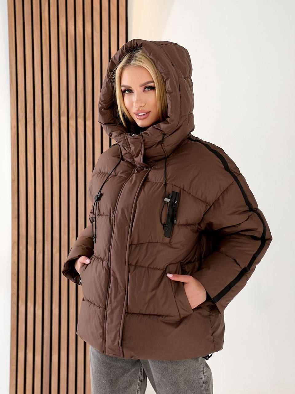 Woman wearing a brown winter coat with a hood against a white background