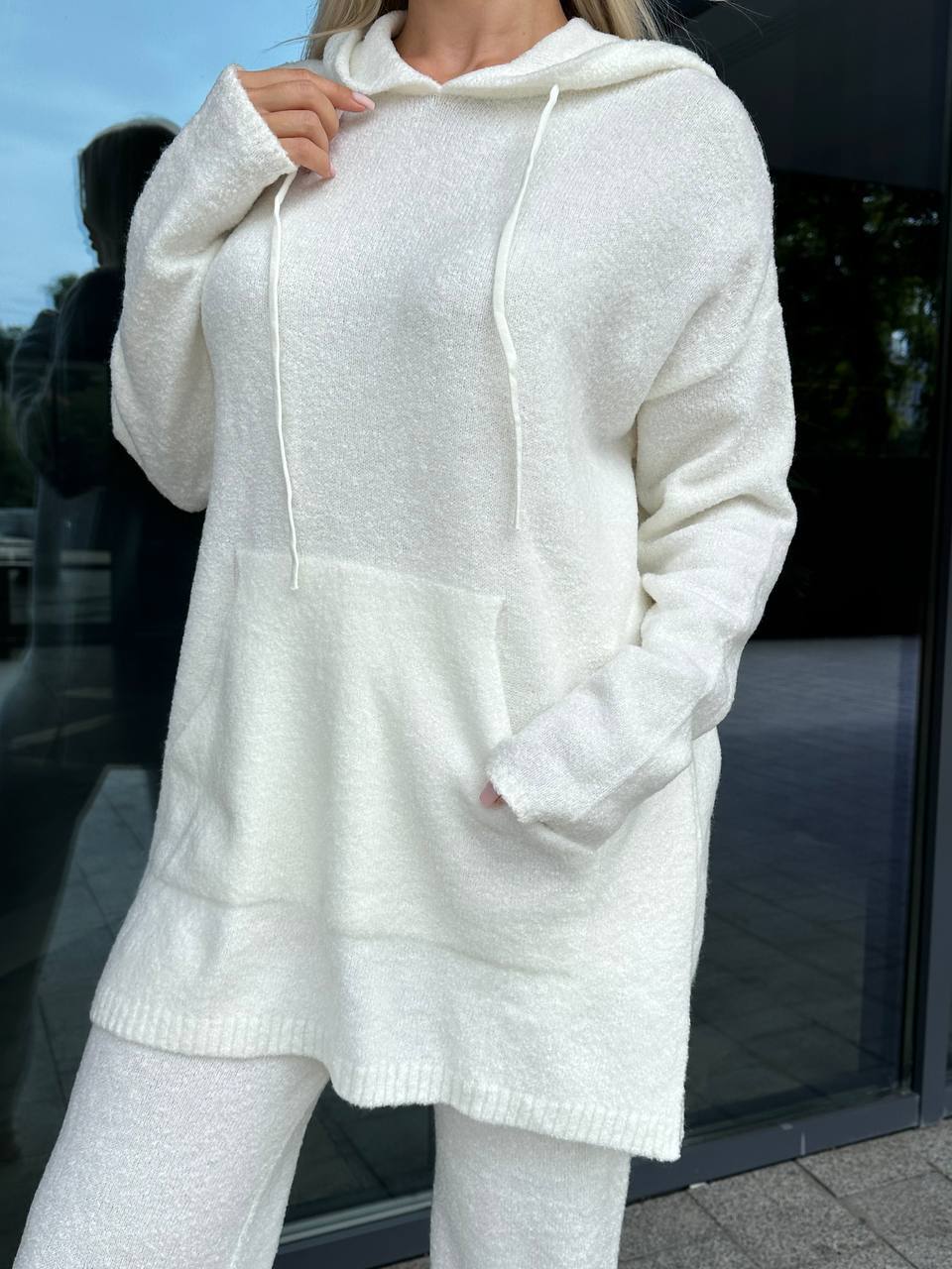 Person wearing a white hoodie and pants in an outdoor setting