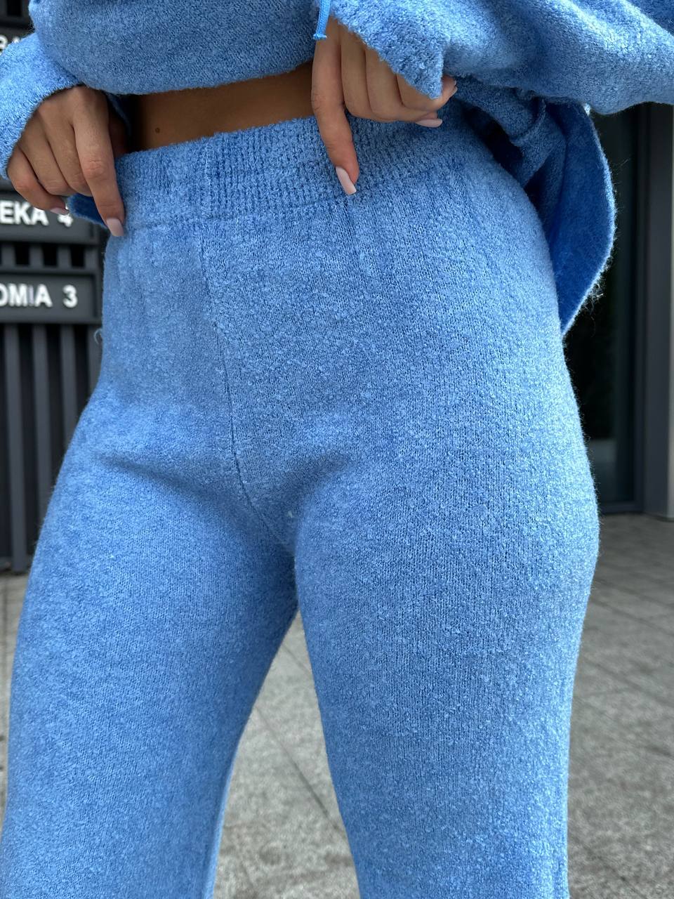 Person wearing blue knitted pants with a blurred background