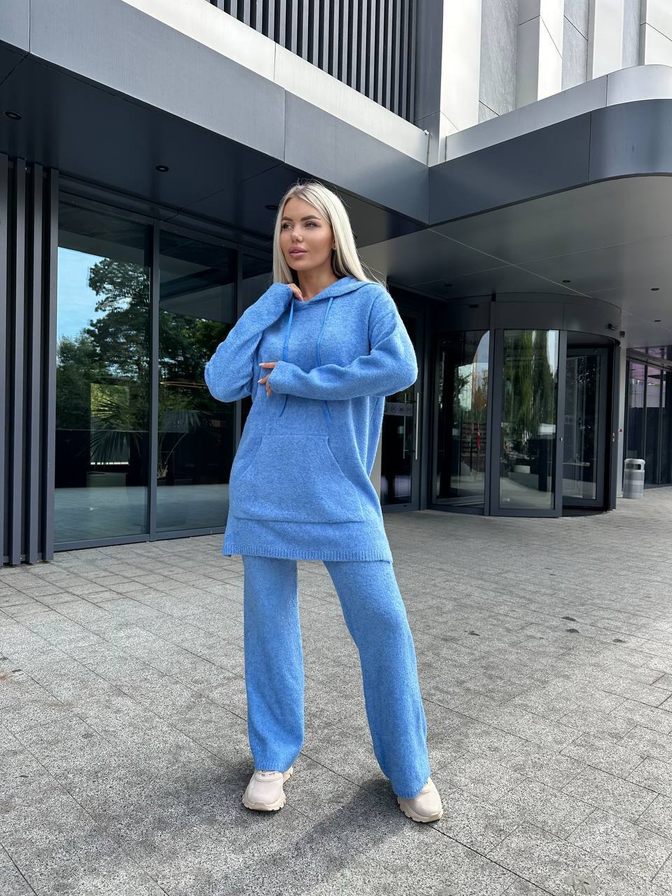 Person wearing a blue outfit standing in front of a modern building.