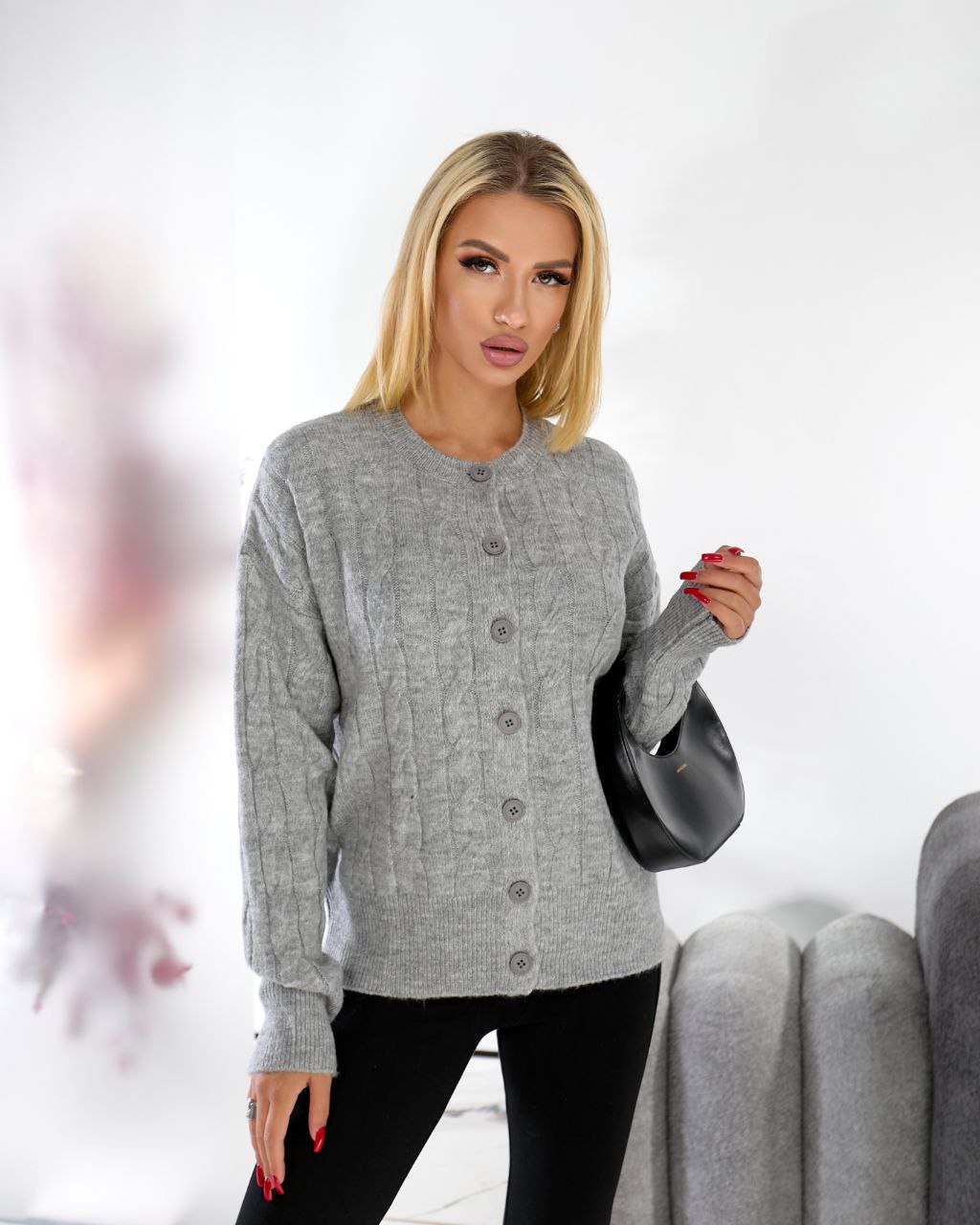 Woman wearing a gray cardigan with a blurred background