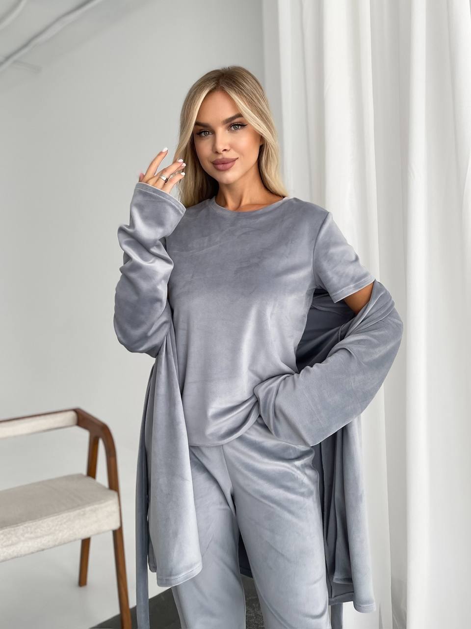 Woman wearing a gray outfit in a minimalistic room.