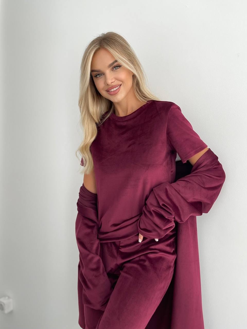 Woman wearing a burgundy outfit with cut-out design on a plain background