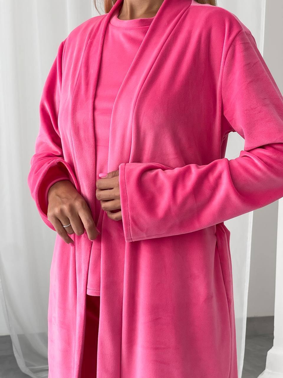 Person wearing a bright pink robe against a white background