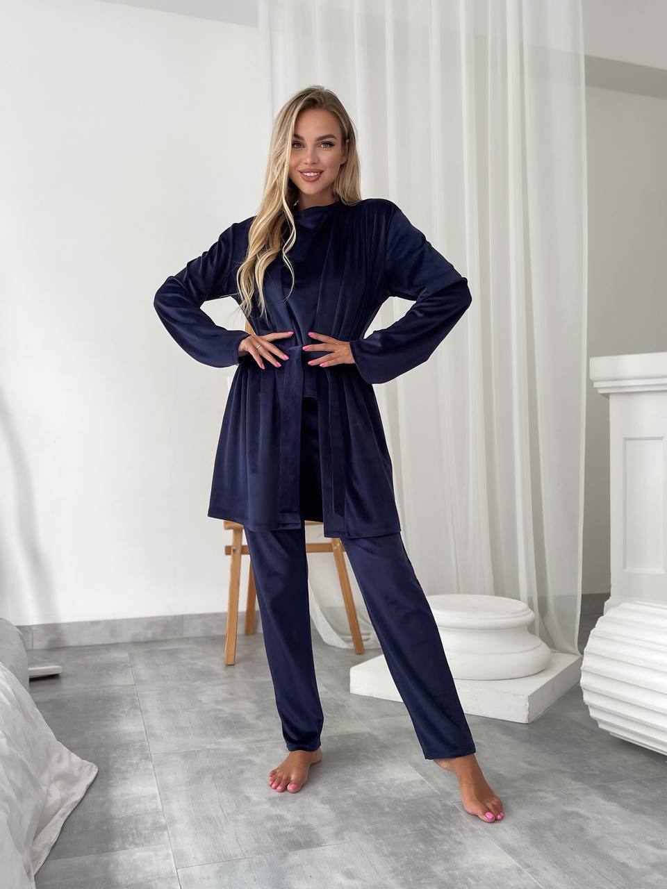 Woman wearing a navy blue outfit in a minimalistic room.