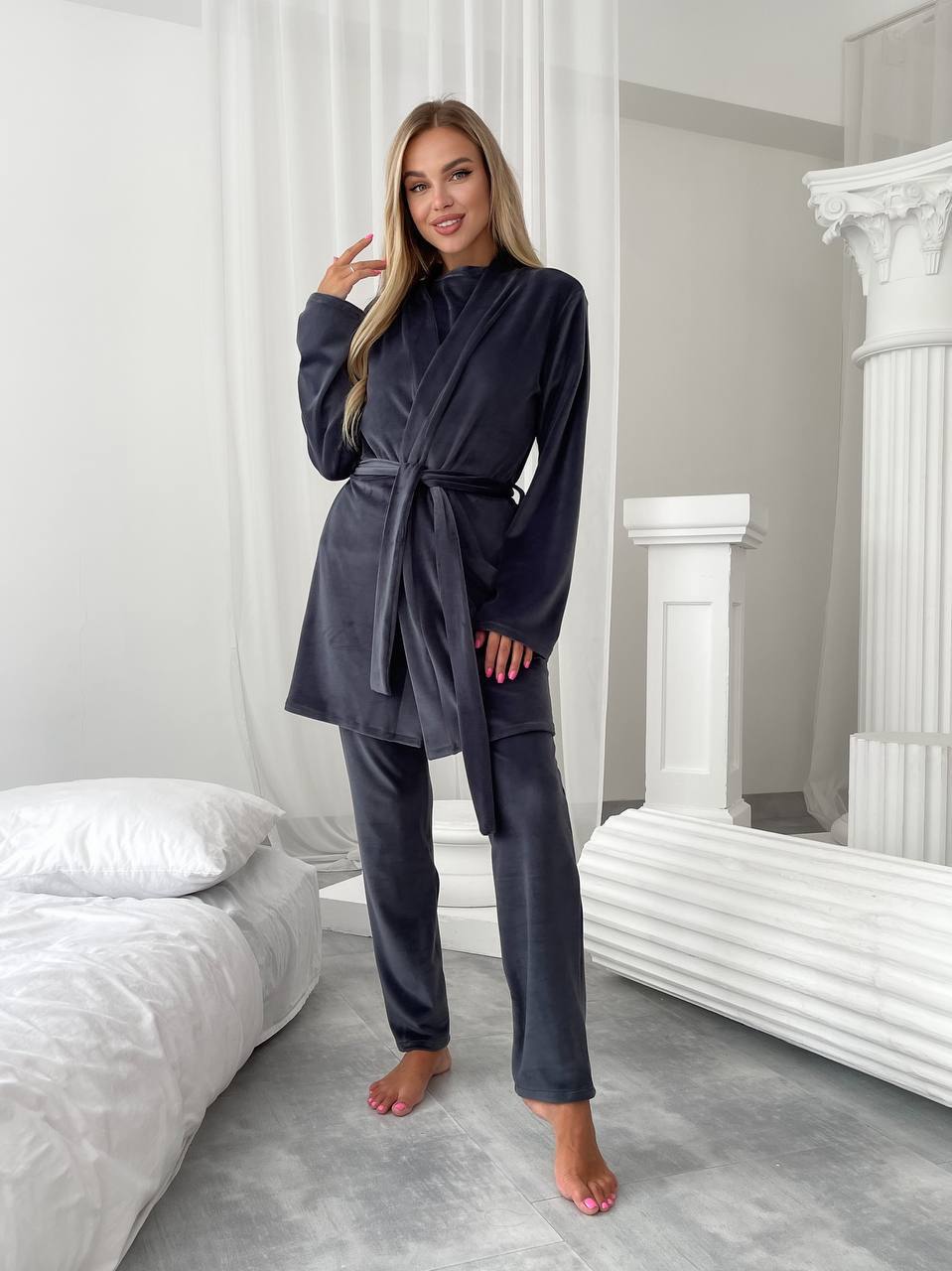 Woman wearing a dark gray robe in a bedroom setting
