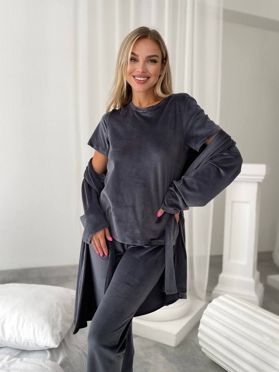 Woman wearing a dark gray outfit in a minimalistic room with white walls and furniture.