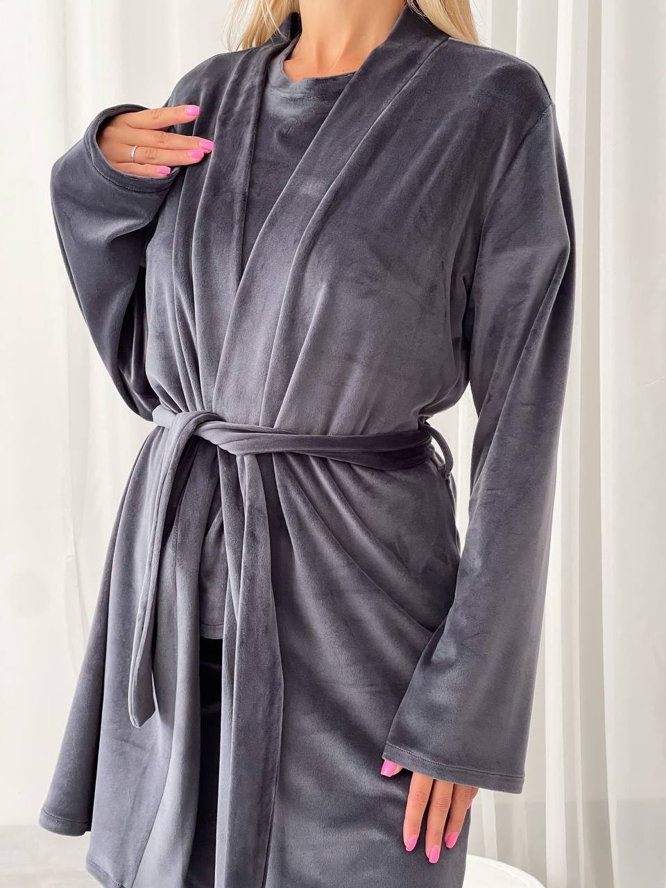 Person wearing a gray robe with a white curtain background