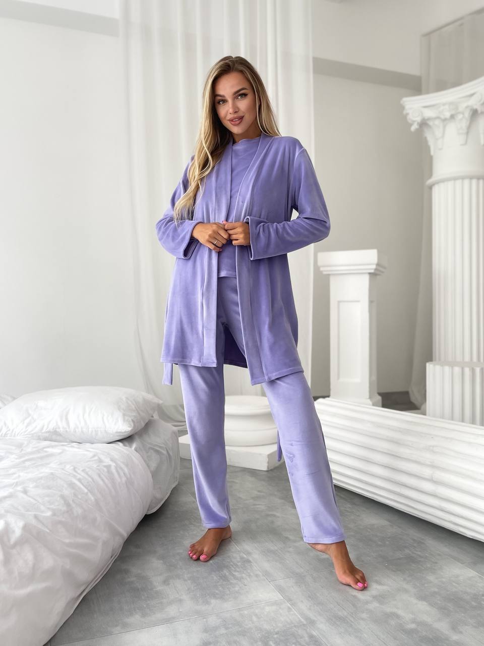 Woman wearing a lavender pajama set in a bedroom.